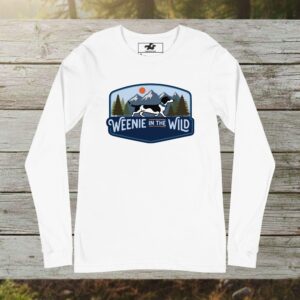 A white long-sleeve shirt featuring the "Weenie in the Wild" graphic: a dachshund silhouette standing before a minimalist mountain range and retro sunset.